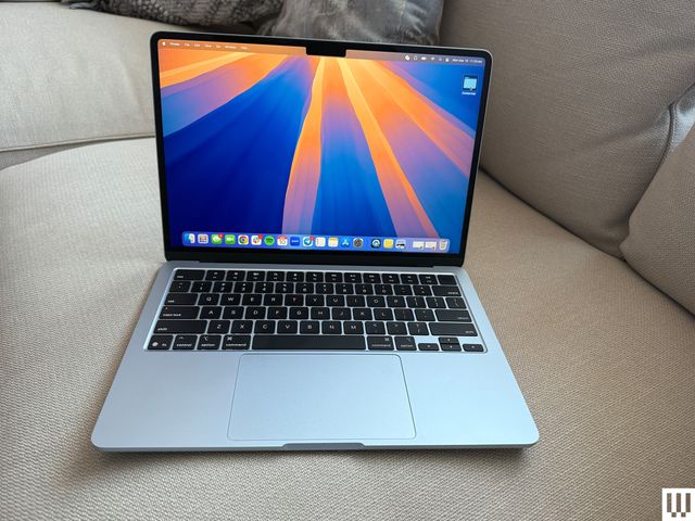 Front view of an open Apple MacBook Air 13inch 2025  laptop sitting on a couch with the screen showing the desktop